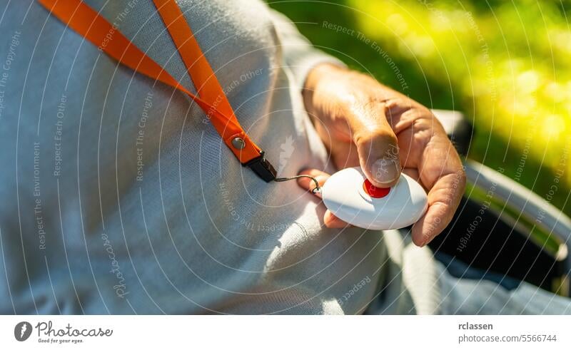 Elderly person pressing emergency Button in his Hand outside in a wheelchair. Emergency call system concept image. hand medical alarm system emergency call