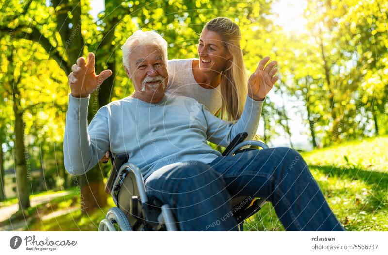 Happy daughter visiting her grandfather in nursing home having a walk with him in the park in a wheelchair. Joyful moments concept image nurse summer joy