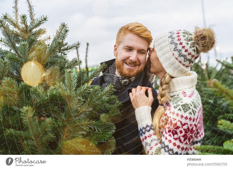 Couple Choosing Christmas Tree Together at a market, she whispers something in his ear surprised family happy redhead tradition choice smile man love couple