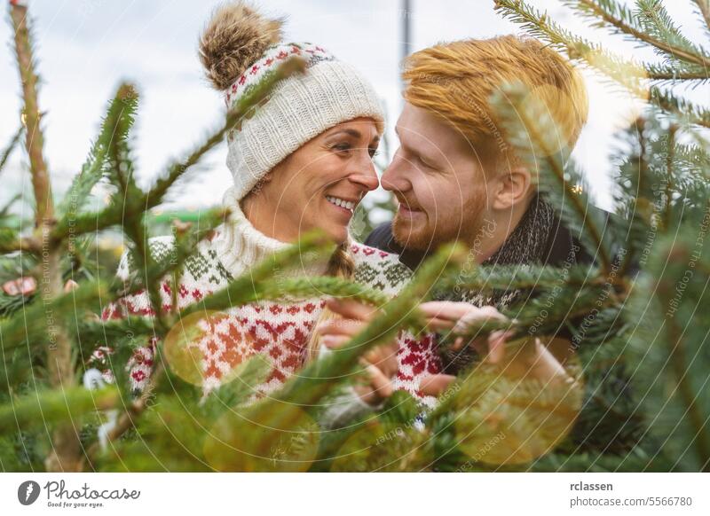 Couple in love buying christmas tree at street market look at kiss family happy redhead tradition choice smile man love couple purchase farm pine tree norway
