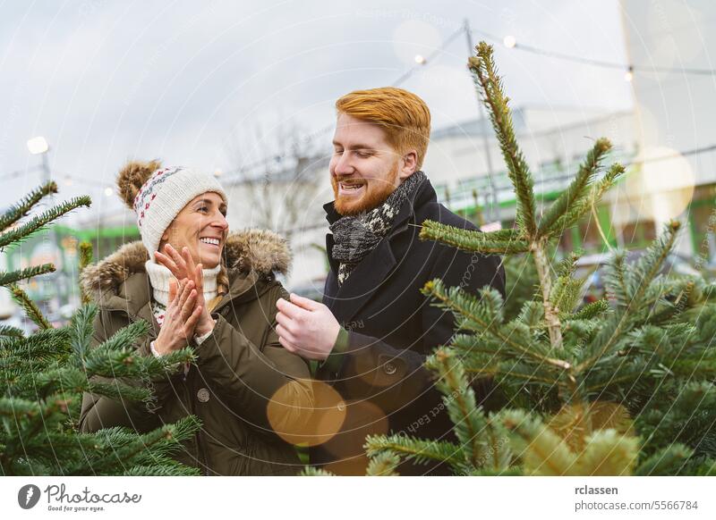 Happy Couple Choosing Christmas Tree Together at a market surprised family happy skeptical redhead tradition choice smile man love couple purchase farm