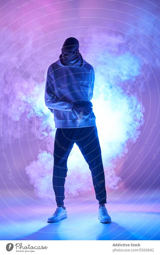 Bald stylish man standing over smoke and glowing light model bald full body casual attire lifestyle outfit posing self-assured trendy confident individuality