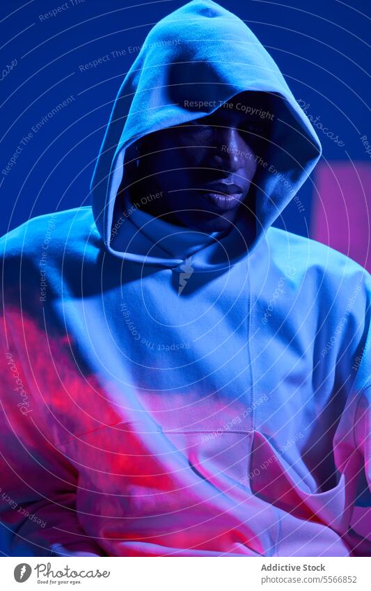 Man in hooded jacket looking away thoughtfully man young serious studio shot illuminate light portrait thinking fashion cool color pensive model self-assured