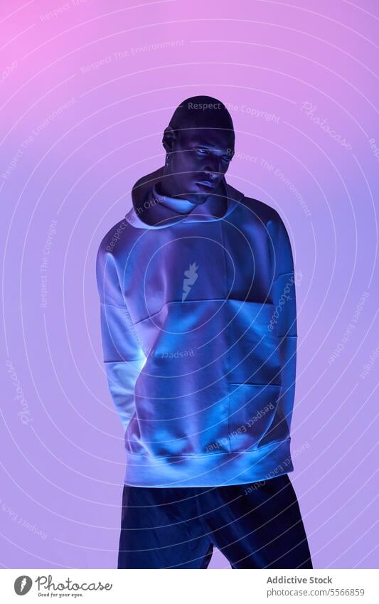 Bald stylish man standing over pink light model bald glowing casual attire lifestyle outfit posing self-assured trendy confident individuality appearance