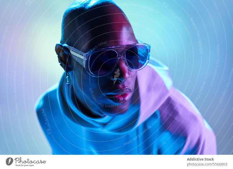 Stylish black young man with sunglasses in studio serious bald earring studio shot modern illuminate light side view confident piercing model hipster nose style