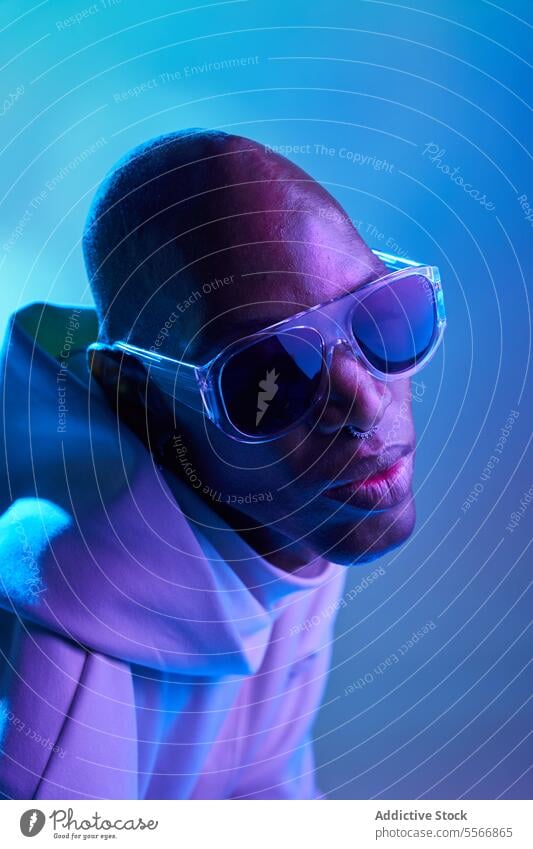 Stylish black young man with sunglasses in studio serious bald earring studio shot modern illuminate light side view confident piercing model hipster nose style