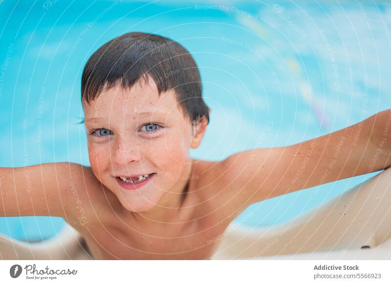 Smiling boy looking at the camera on the pool slide. Boy smile blue eyes edge water lean swim child joy summer wet skin swimwear caucasian portrait outdoor