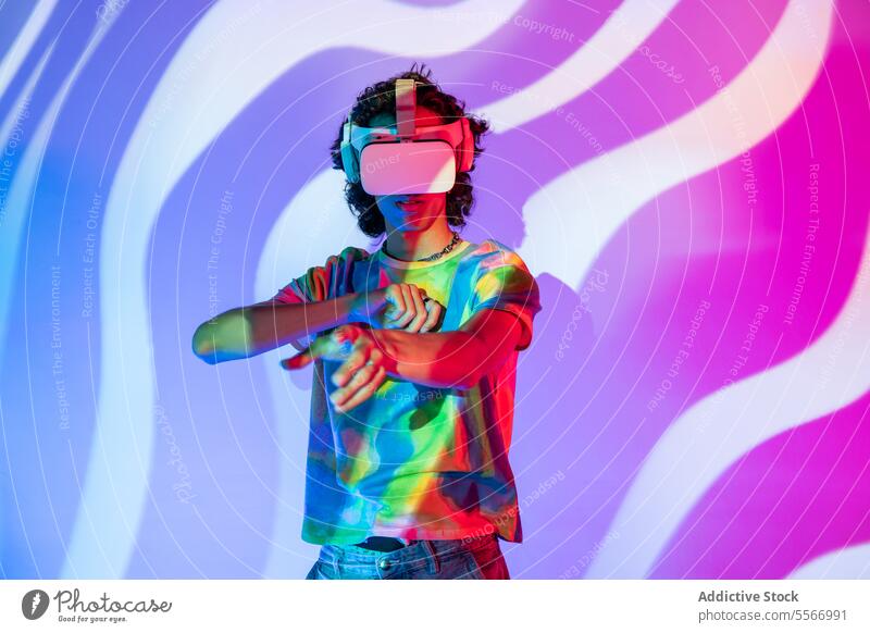 Latin man in tie-dye explores virtual reality with headset glasses shirt vr latin interact blue purple backdrop swirl technology fashion jeans model engage