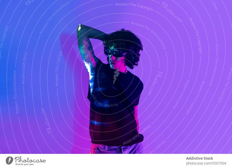 Curly-haired latin man posing under neon lights on purple background curly hair pose vibrant dynamic fashion style young male colorful modern illuminated
