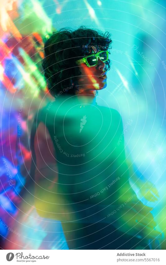 Figure aglow with neon green sunglasses man latin portrait curly hair light figure radiance young fashion ambiance style reflection design color elegance mood