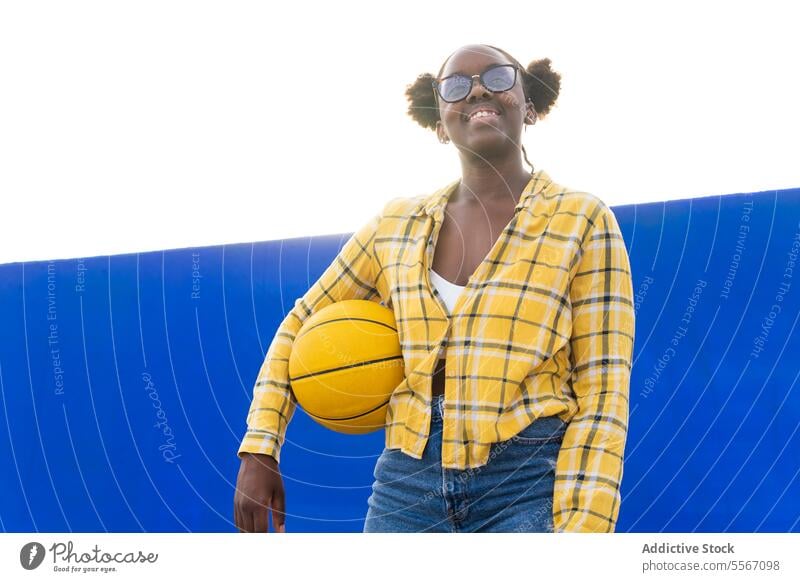 Happy Thoughtful Woman Holding Basketball During Sunny Day Smile Eyeglasses Looking Away Sunlight Standing Casual Wall Blue Yellow Plaid Shirt Sport Leisure