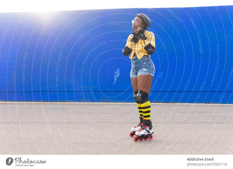 Woman Fastening Helmet While Standing On Rink At Roller Skate Park Skating Preparation Casual Blue Wall Sport Practice Leisure Weekend Activity Summer Lifestyle