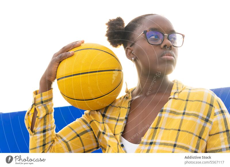 Thoughtful Woman Holding Basketball During Sunny Day Serious Eyeglasses Looking Away Sunlight Casual Yellow Plaid Shirt Sport Leisure Weekend Activity Summer