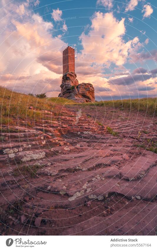 Sunset at the ancient tower sunset boulder stone pathway sky cloud landmark history Zafra Castle Cuenca open air grass terrain horizon structure tall old rock
