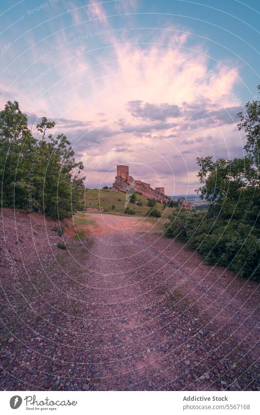 Path to the ancient castle path gravel Zafra Castle Cuenca open air sky dusk hill tree mesmerizing cloudy fortress medieval landmark journey approach heritage