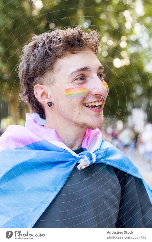 Joyful pride celebration man joy expression portrait pastel flag rainbow cheek LGBTQ young nature smile outdoors festival symbol paint unity acceptance rights