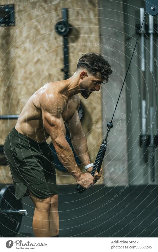 Resistance training intensity man gym resistance rope shirtless green shorts torso focus stretch muscle hand urban intense chiseled workout fitness strength