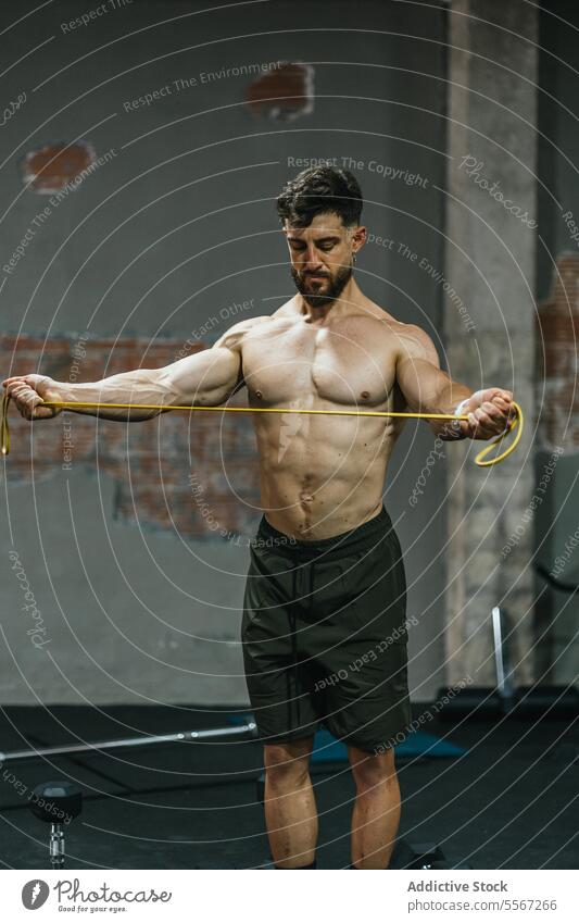 Focused resistance stretch man gym band yellow brick gray wall muscle determination workout training fitness beard posture athletic strength focus tension pull