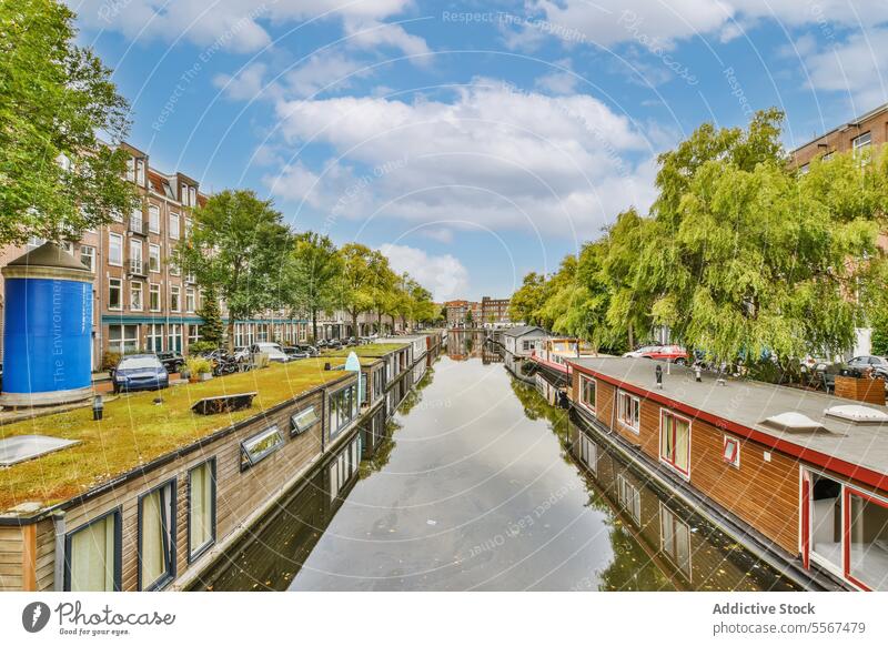 Houseboats moored on canal in city water blue sky tree building structure architecture day travel outside exterior daytime tourism window apartment residential