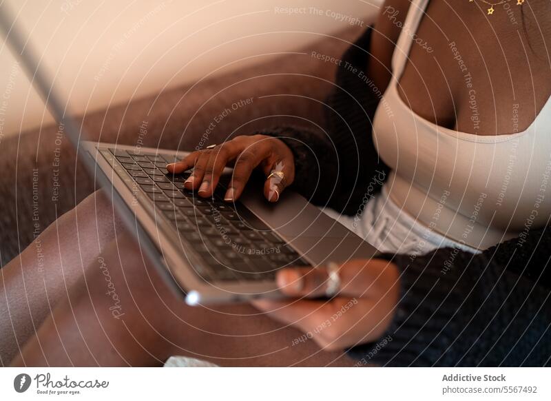 Anonymous African lady working on laptop African American typing relaxed home keyboard focus gold ring close-up ethnic comfort black remote technology