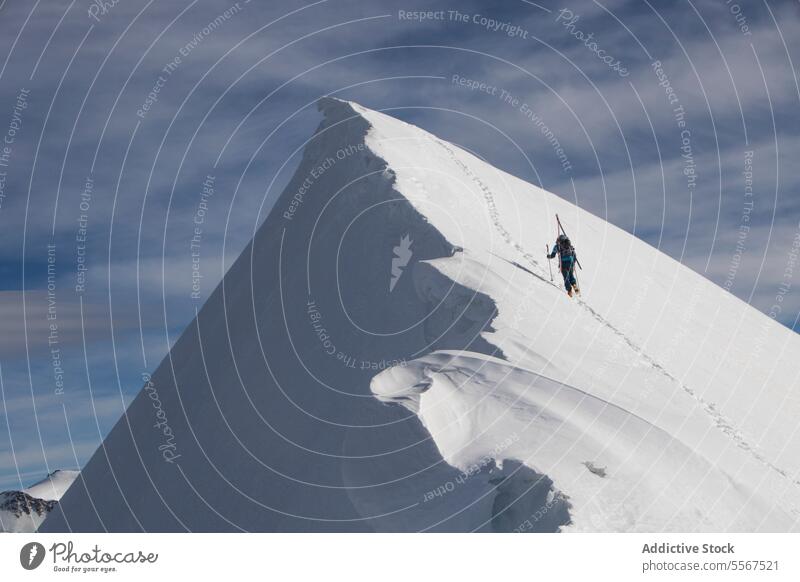 Unrecognizable person climbing snowcapped mountain peak skier unrecognizable challenge effort pole covering sky back view skiing reaching anonymous vacation
