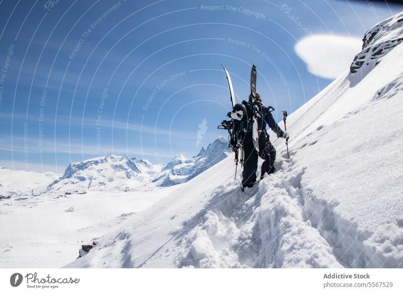 Unrecognizable person climbing snowcapped mountain skier unrecognizable challenge pole covering back view skiing effort anonymous vacation active recreation