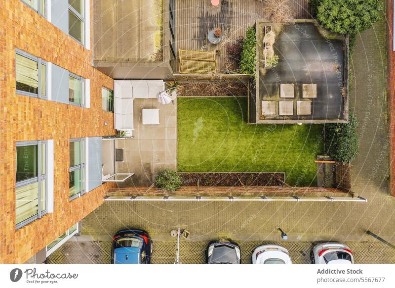 Aerial view of building and backyard with parking lot apartment furniture grass lawn shed car vehicle garden exterior window brick wall aerial view modern couch
