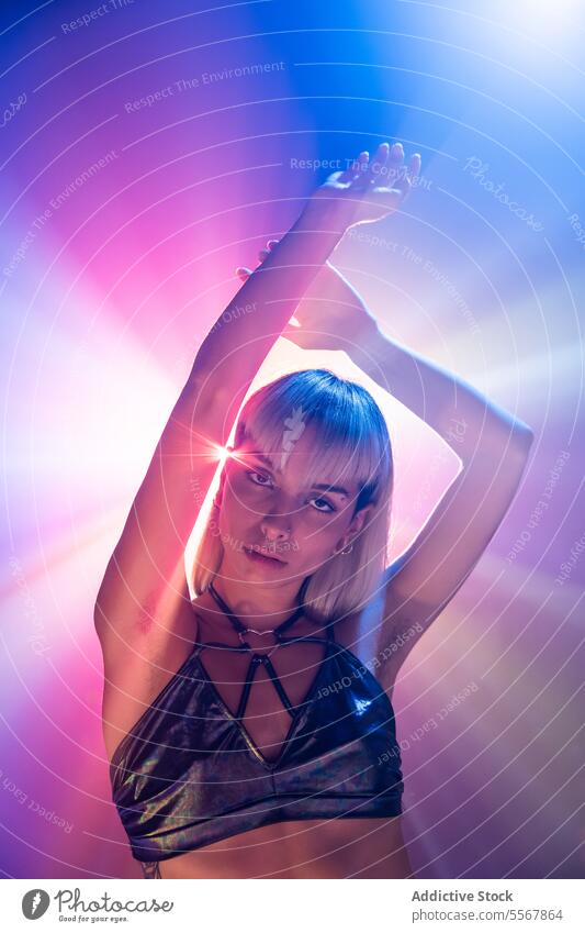 Portrait of attractive woman with arms raised model sensual outfit portrait glow light charming young bangs makeup confident illuminate bright serious posing