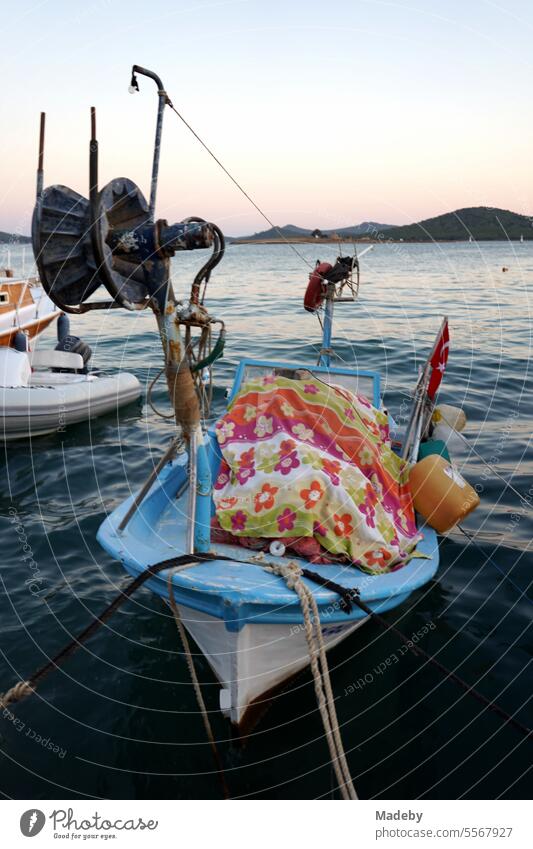 Romantic evening atmosphere by the sea with fishing boat and pulley in the light of the evening sun with pier at the harbor in the bay of Ayvalik on the Aegean Sea in the province of Balikesir in Turkey