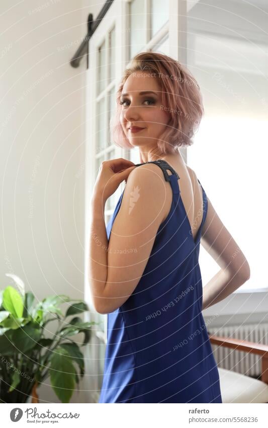 Rear view of a pretty fashion model wearing a blue dress while standing at home rear view redhead caucasian woman female person indoor young beautiful portrait