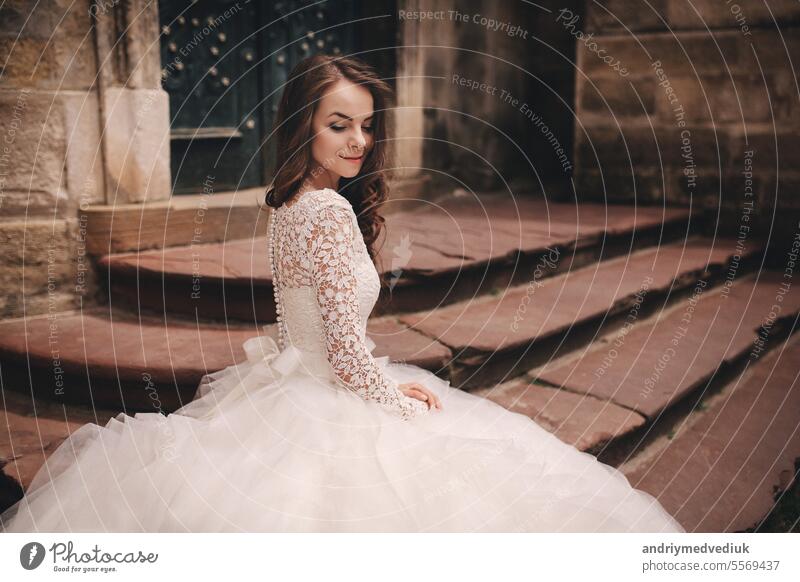 portrait of a beautiful young bride in a white wedding dress with long hair in the old European city. Woman near old building. wedding day girl town woman