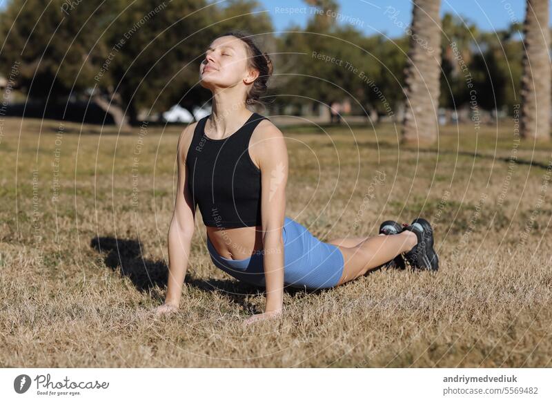 World health day. Beautiful fit young woman in sporswear working out outdoors at park, doing stretching exercises standing in pose dog muzzle up, sun salutation complex. Upward-Facing Dog Breakdown