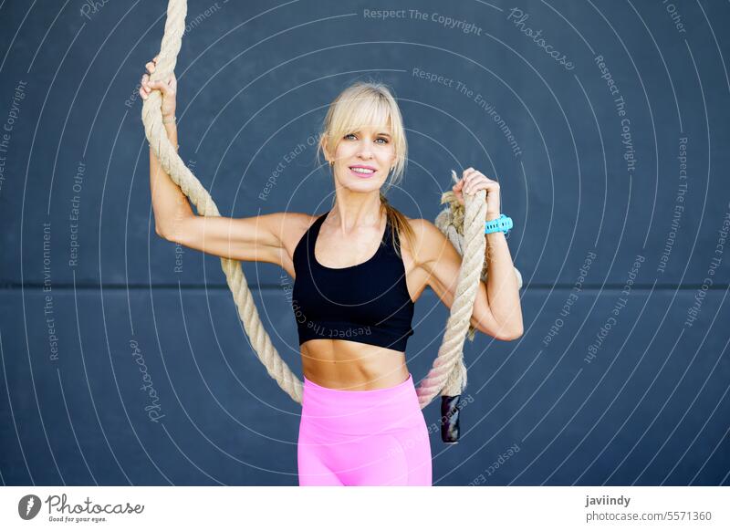 Fit woman with gymnastic rope in gym confident climber training exercise fit workout activity activewear fitness wellness blond athlete healthy physical