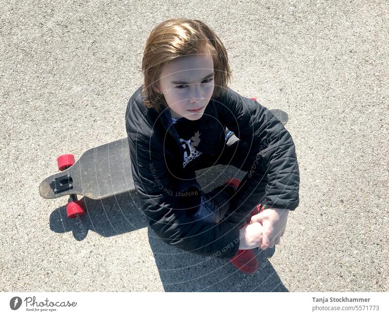 Boy sitting with skateboard Boy (child) boy Skateboard sedentary Sports hobby serious look Athletic Leisure and hobbies Leisure activity recreational activity