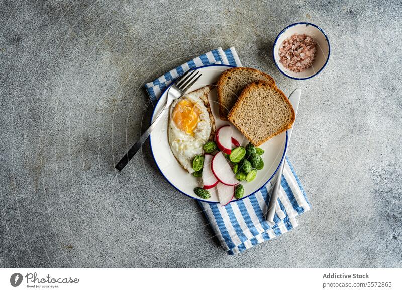 Healthy lunch plate on striped cloth breakfast egg bread radish vegetable green blue white bowl pink salt gray texture backdrop meal morning nourishment yolk