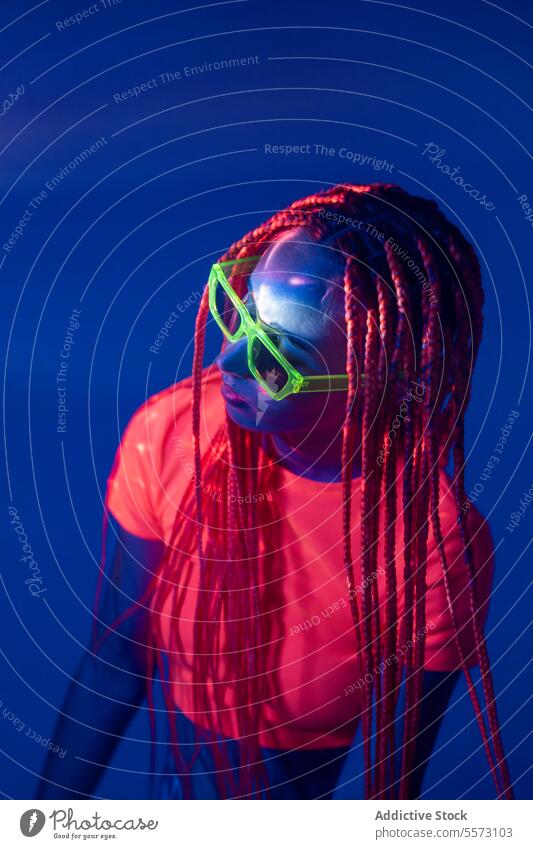 Woman with orange braids standing in neon lights woman young portrait metaverse afro braids abstract serious confident individuality appearance sunglasses
