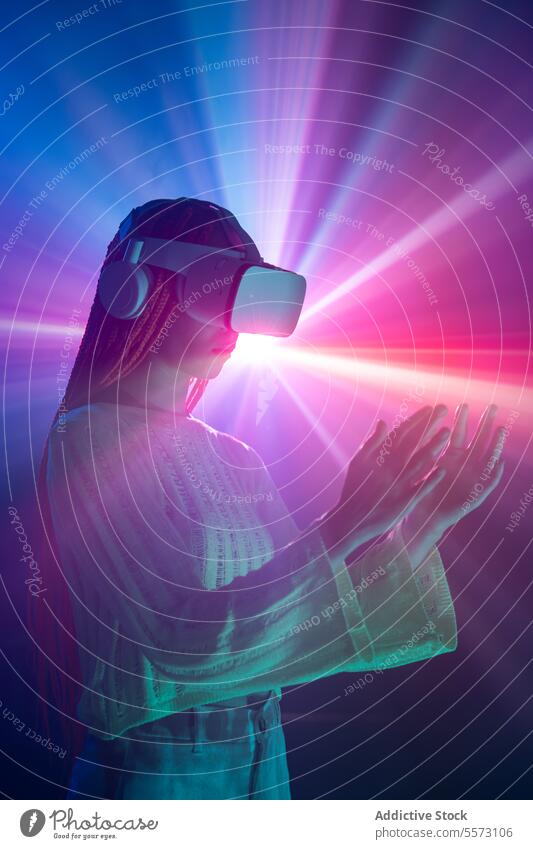 Woman in VR goggles gesturing over neon lights woman vr virtual reality gesture orange braids headset technology immerse innovation futuristic metaverse