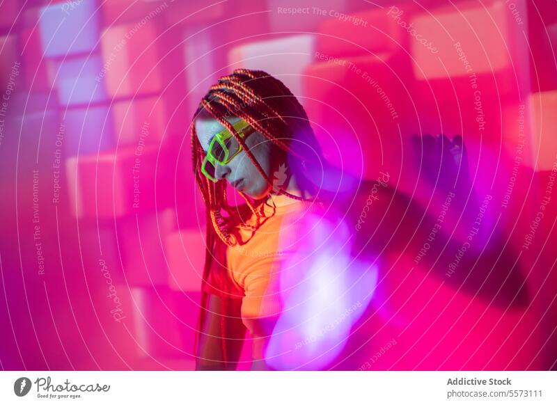 Woman with orange braids standing in neon lights woman young portrait metaverse afro braids abstract serious confident individuality appearance sunglasses