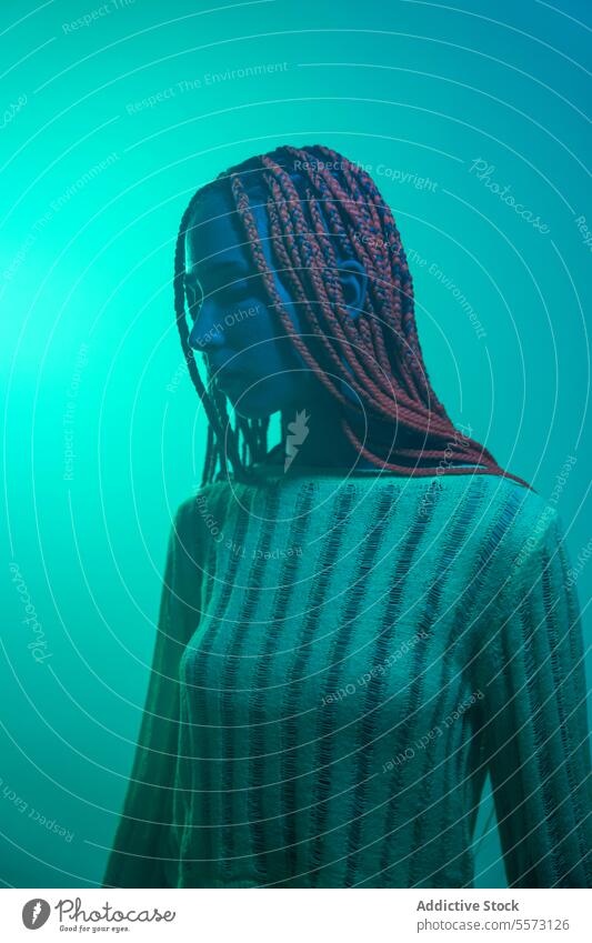 Thoughtful sad woman standing in green light young braids contemplate serious blue neon glowing dreaming thinking pensive expression wonder imagine lonely