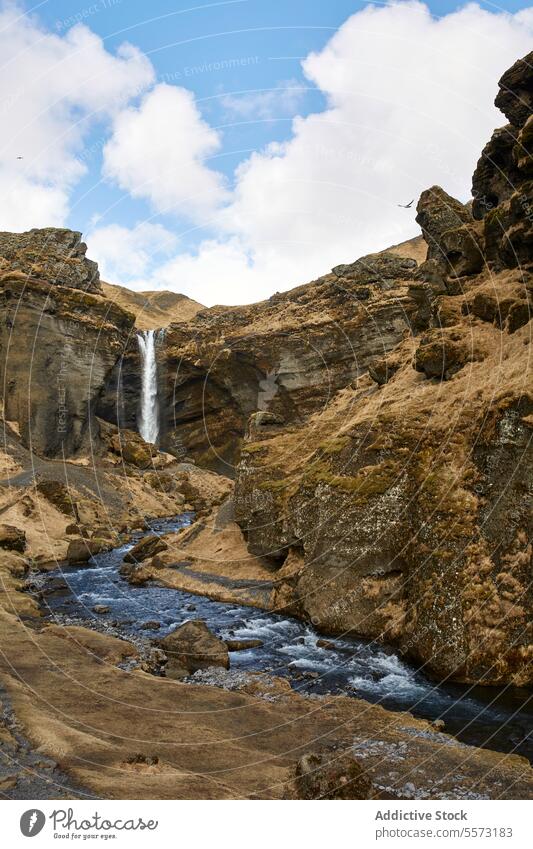 Icelandic cliffside waterfall and stream sky cloud cascade rock rugged blue flow nature outdoors scenic landmark natural terrain beauty picturesque flowing