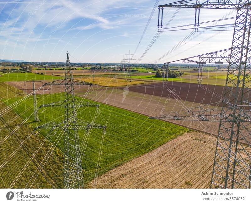 Aerial view of between power poles with power lines to horizon aerial shot power pylons drone perspective fields multiple high voltage pylons rural many