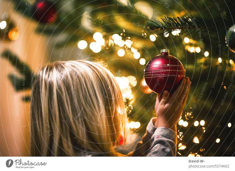 Child looking at a Christmas bauble on the Christmas tree explore Cute Anticipation Glitter Ball Marvel Christmas tree decorations Tradition Festive reverence