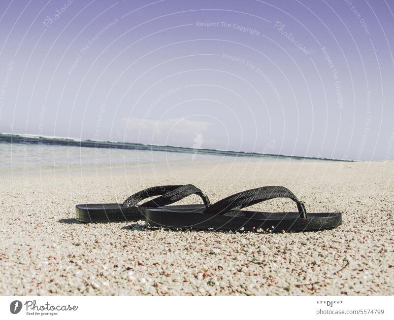 Flip-flops on the beach in front of the sea. Blue sky in the background. Black toe step Beach Ocean Summer Relaxation flip Flops holidays vacation travel