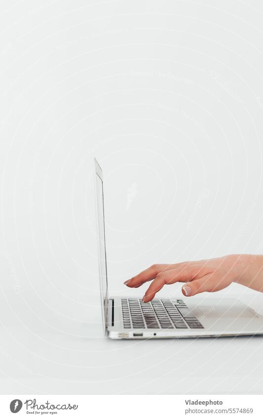 Female hand carefully typing buttons on the laptop keyboard, side view, white background, minimalism computer work business press finger desktop technology