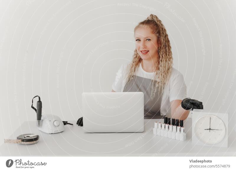 Woman Professional Manicurist at her Desk Works with a Laptop. Sign up for manicure Services, Freelancer Work Schedule salon nail manicurist laptop entry