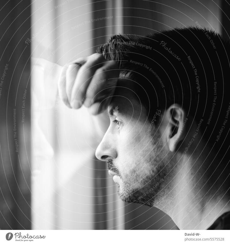Thoughtful man looks outside through the window Man Meditative view outside Window void Worries Fears Emotions Fear of the future Loneliness Sadness Face