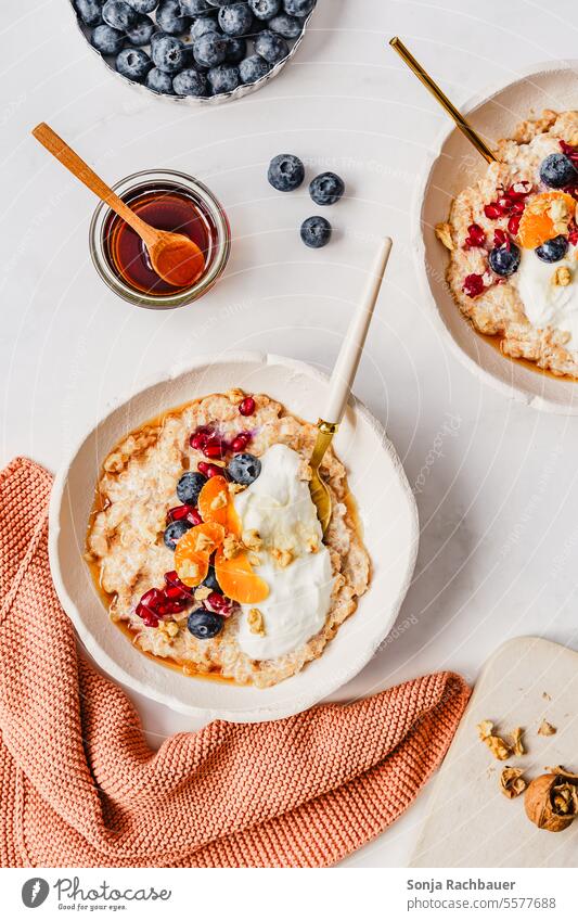 Porridge with fruit and honey in two bowls. Top view. porridge Oat flakes Breakfast Tangerine blueberry Milk warm Healthy Diet Bowl Spoon Food Cereal Morning