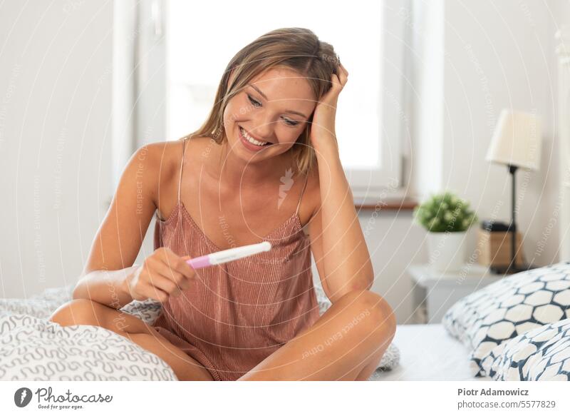 Young happy woman because of the pregnancy test result ovulation pregnant positive teenager young adult anticipation casual caucasian close-up smiling expecting