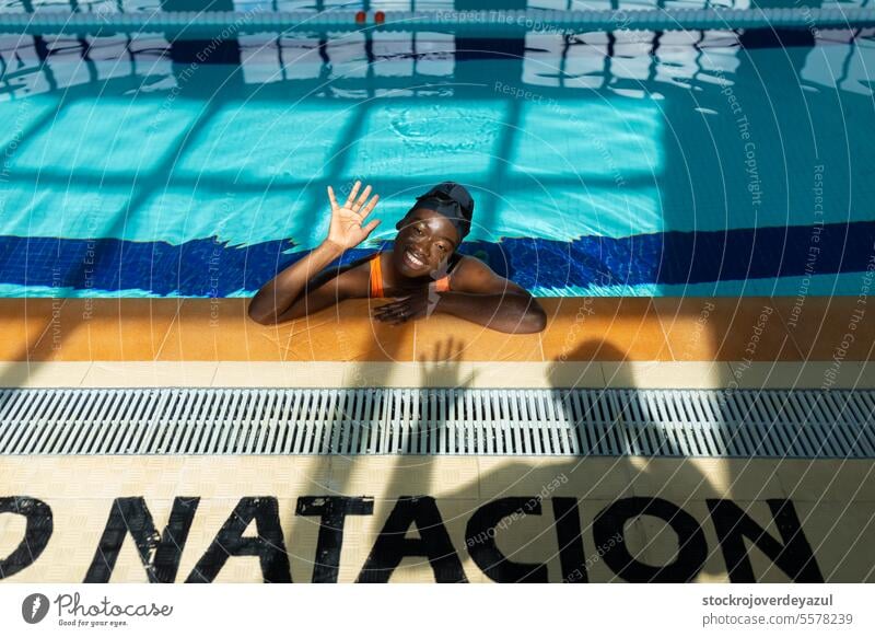 Black young woman waving relaxed by the curb during a bath at the swimming pool water person sport swimmer active black female heated swimsuit orange healthy