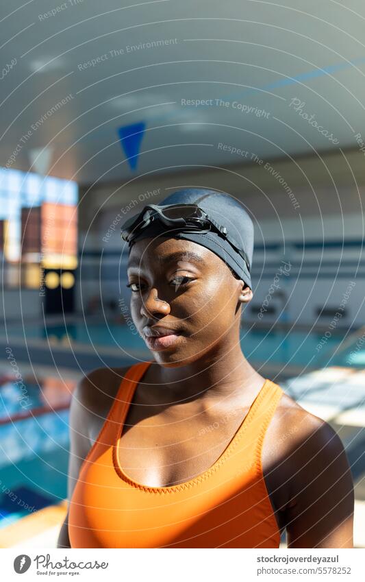 Close up portrait of a black young woman looking at camera at the swimming pool swimmer sport female heated swimsuit orange healthy smiling blue lifestyle